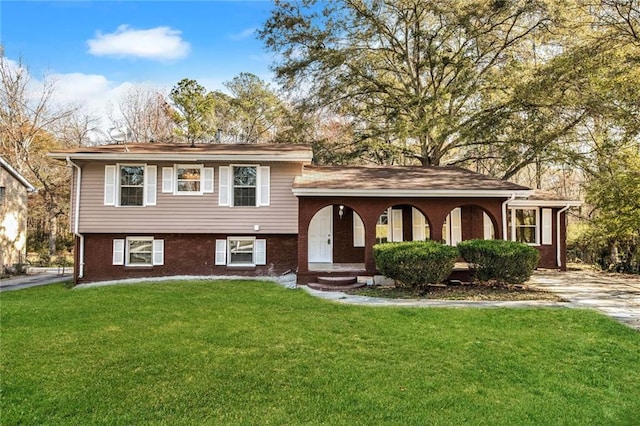 tri-level home with brick siding and a front yard