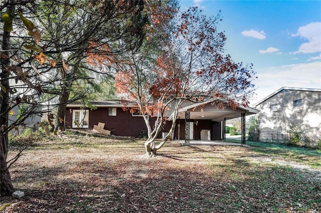 rear view of house with french doors, a carport, and fence