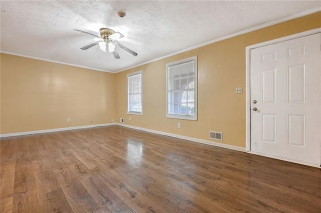 empty room with visible vents, a ceiling fan, wood finished floors, and crown molding