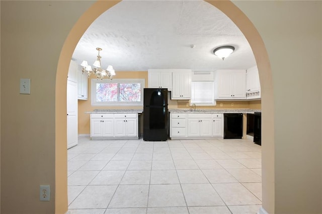 kitchen with arched walkways, black appliances, white cabinets, and light countertops