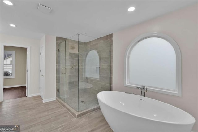 250 Stonecreek Pkwy, Covington, GA 30016 - bathroom featuring a freestanding bath, a shower stall, recessed lighting, and wood finished floors
