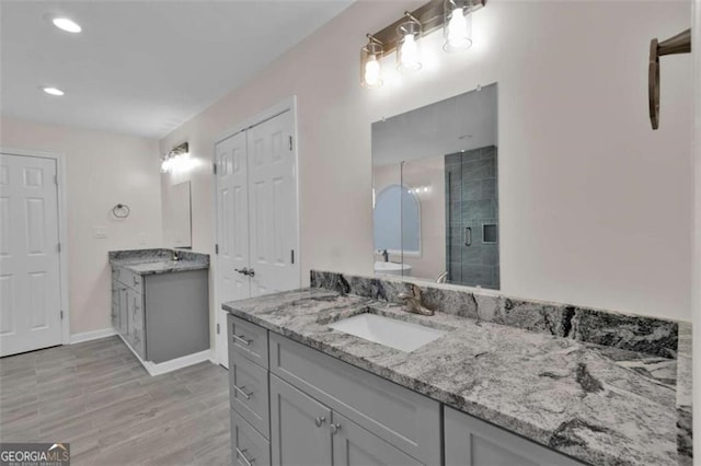250 Stonecreek Pkwy, Covington, GA 30016 - bathroom with two vanities, a shower stall, recessed lighting, and wood finished floors