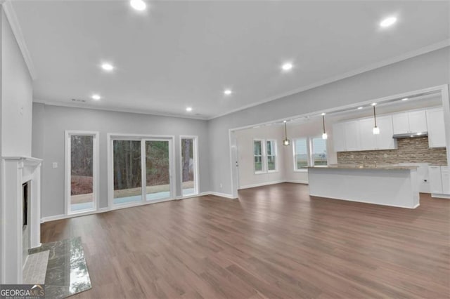 250 Stonecreek Pkwy, Covington, GA 30016 - unfurnished living room featuring ornamental molding, dark wood-type flooring, recessed lighting, and a fireplace with flush hearth
