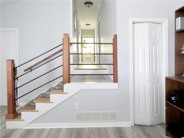 stairway with visible vents and wood finished floors