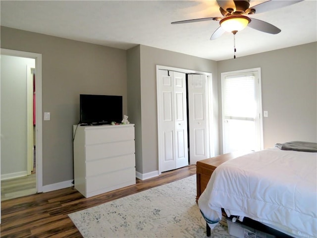 bedroom featuring dark wood finished floors, a closet, baseboards, and a ceiling fan