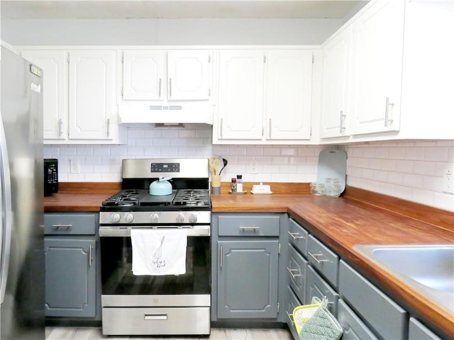 kitchen featuring under cabinet range hood, gray cabinets, butcher block counters, and stainless steel appliances