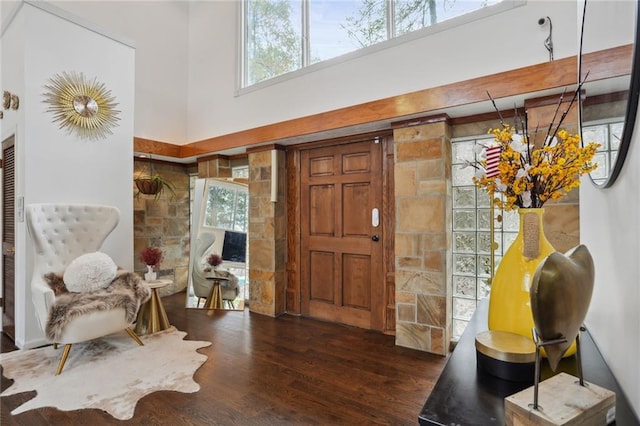 entrance foyer featuring beam ceiling, dark hardwood / wood-style flooring, and a high ceiling