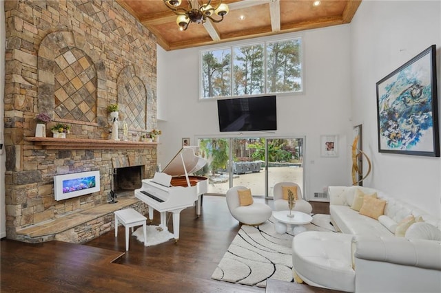 living room featuring coffered ceiling, a stone fireplace, dark hardwood / wood-style floors, a notable chandelier, and a towering ceiling