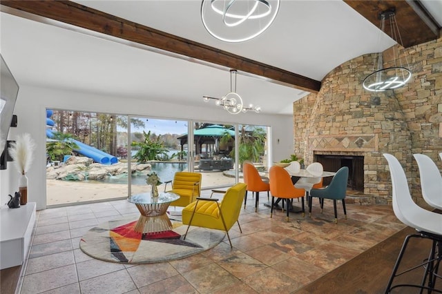 dining room featuring vaulted ceiling with beams, a notable chandelier, and a stone fireplace