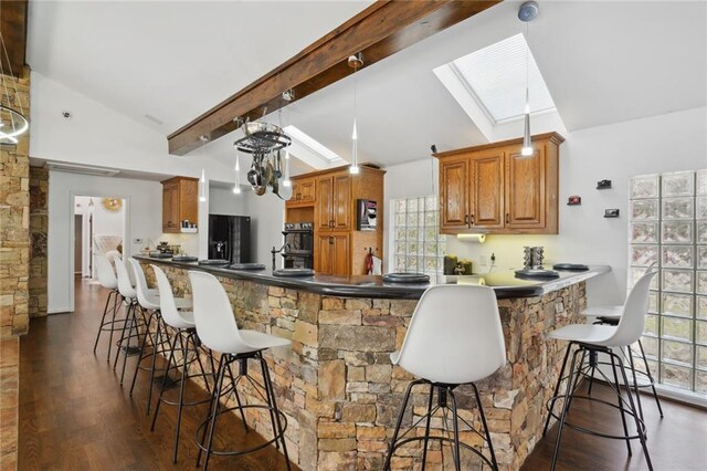 kitchen with plenty of natural light, dark hardwood / wood-style flooring, kitchen peninsula, and a skylight