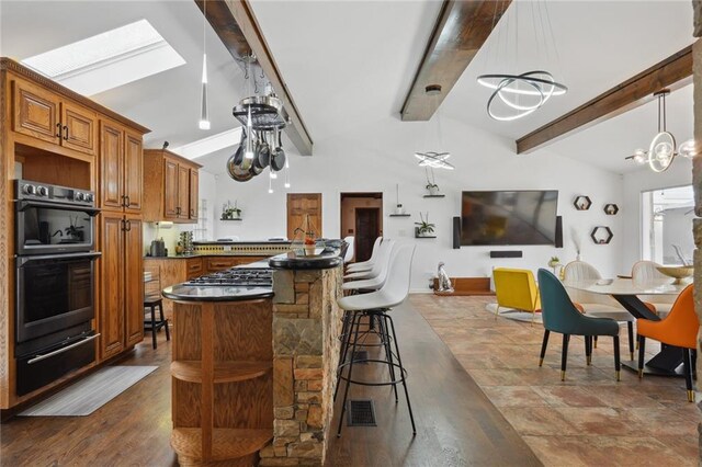 kitchen featuring double oven, pendant lighting, a chandelier, a breakfast bar, and vaulted ceiling with skylight