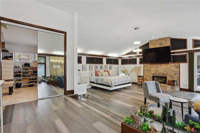 bedroom featuring a fireplace, wood-type flooring, and vaulted ceiling