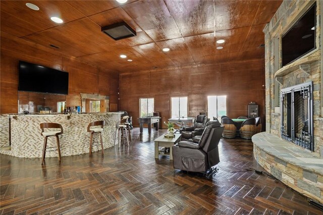living room featuring wood walls, dark parquet flooring, and wood ceiling