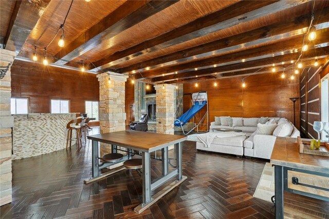 dining room featuring decorative columns, wood ceiling, dark parquet floors, wooden walls, and beamed ceiling