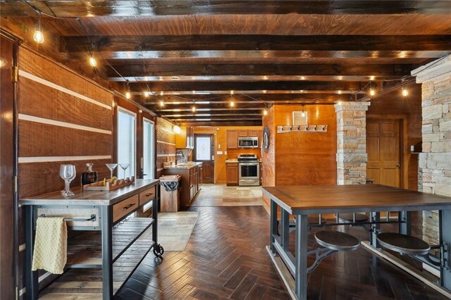 kitchen featuring dark parquet flooring, stainless steel appliances, sink, beamed ceiling, and wood walls