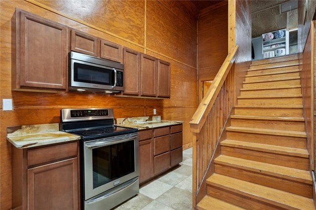 kitchen with light stone countertops, stainless steel appliances, and wooden walls