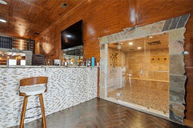 bar featuring dark parquet flooring, wooden ceiling, and wooden walls