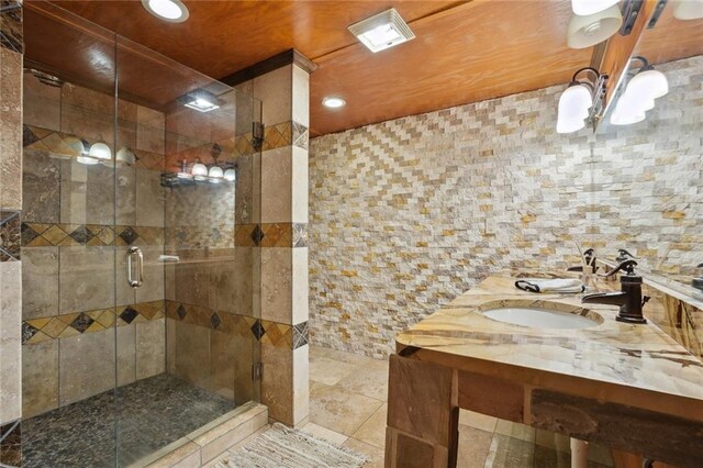 bathroom featuring tile patterned flooring, vanity, a shower with shower door, and tile walls
