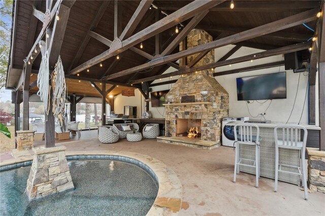 view of patio / terrace with washer / clothes dryer, an outdoor bar, and an outdoor stone fireplace