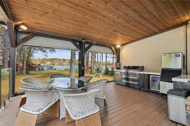 deck featuring an outdoor kitchen, grilling area, and beverage cooler