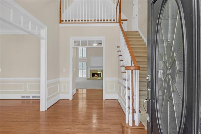 1405 Wilmington Way, Grayson, GA 30017 - foyer with wood finished floors, stairs, a high ceiling, a wainscoted wall, and a glass covered fireplace