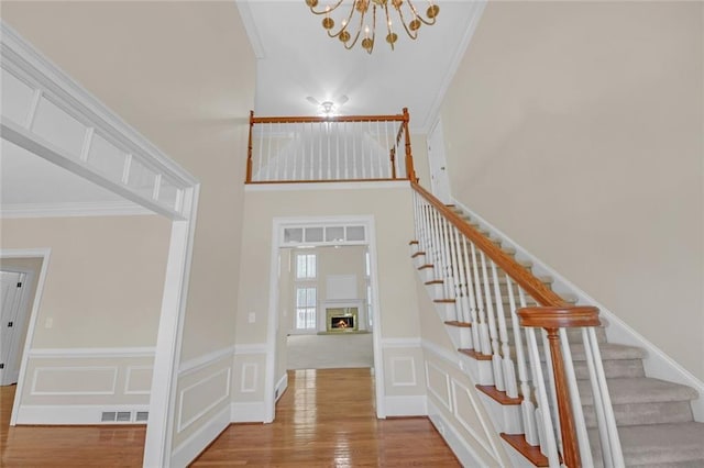 1405 Wilmington Way, Grayson, GA 30017 - staircase with a chandelier, wood finished floors, ornamental molding, and a warm lit fireplace
