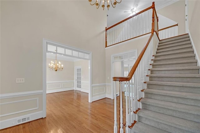 1405 Wilmington Way, Grayson, GA 30017 - stairway featuring a chandelier, wood finished floors, a wainscoted wall, a decorative wall, and a high ceiling