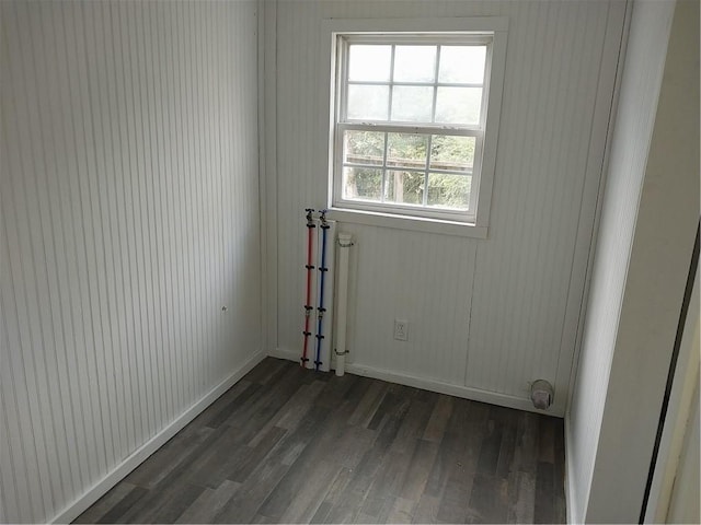 unfurnished room with baseboards and dark wood-type flooring