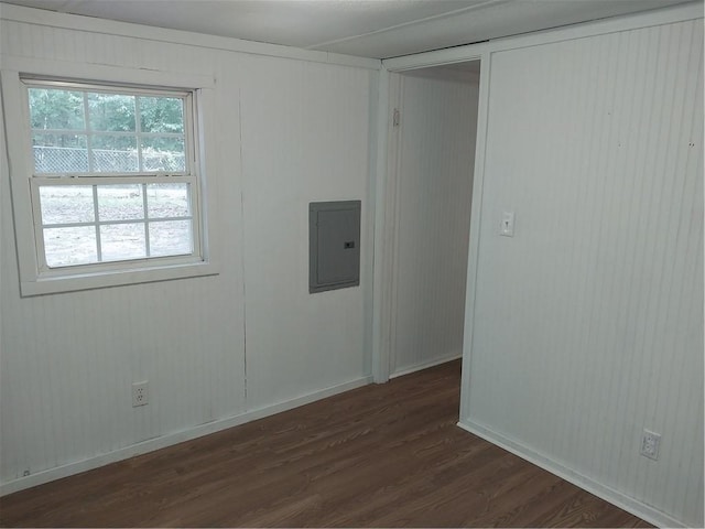 empty room featuring dark wood-style floors, baseboards, and electric panel