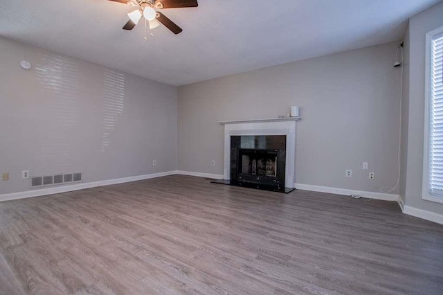 unfurnished living room with hardwood / wood-style flooring, ceiling fan, and a high end fireplace