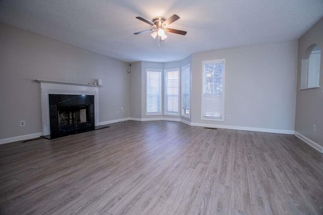 unfurnished living room with hardwood / wood-style flooring, a textured ceiling, a premium fireplace, and ceiling fan