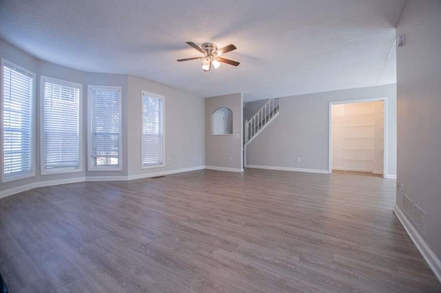 unfurnished living room featuring ceiling fan and dark hardwood / wood-style floors