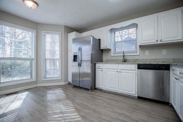 kitchen featuring stainless steel appliances, light stone countertops, and white cabinets