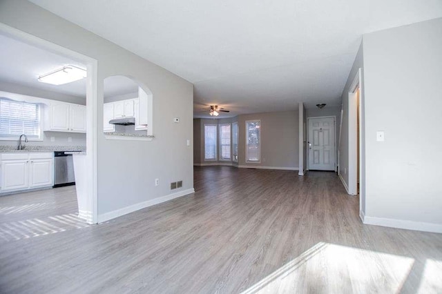 unfurnished living room with ceiling fan, a healthy amount of sunlight, light hardwood / wood-style floors, and sink