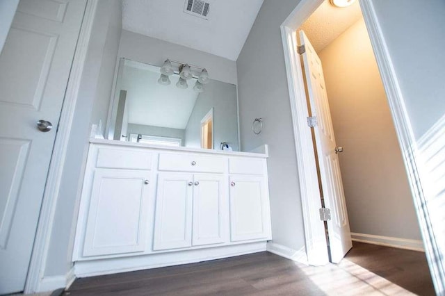 bathroom with vanity, lofted ceiling, and hardwood / wood-style floors