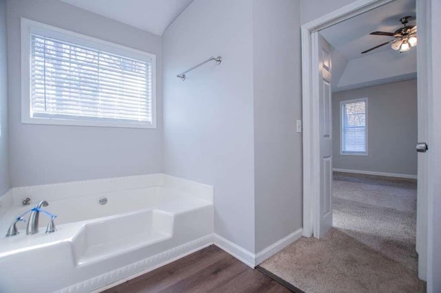 bathroom with hardwood / wood-style floors, a bath, and ceiling fan