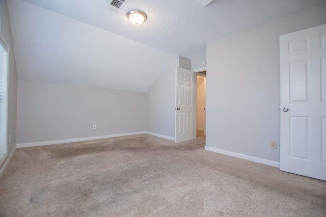 bonus room featuring vaulted ceiling, light carpet, and a textured ceiling