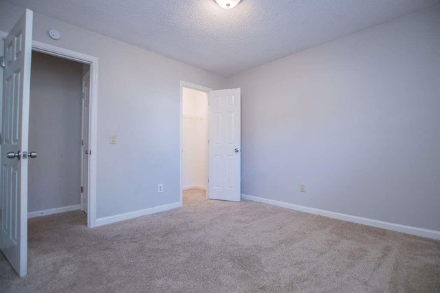 unfurnished bedroom featuring light colored carpet, a closet, and a textured ceiling