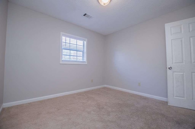 carpeted empty room featuring a textured ceiling