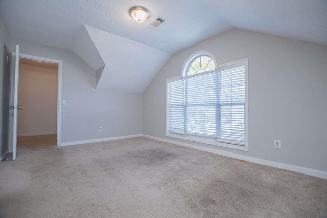 bonus room with light colored carpet and vaulted ceiling