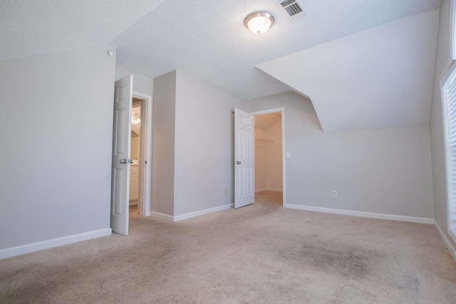 bonus room featuring lofted ceiling, light colored carpet, and a textured ceiling