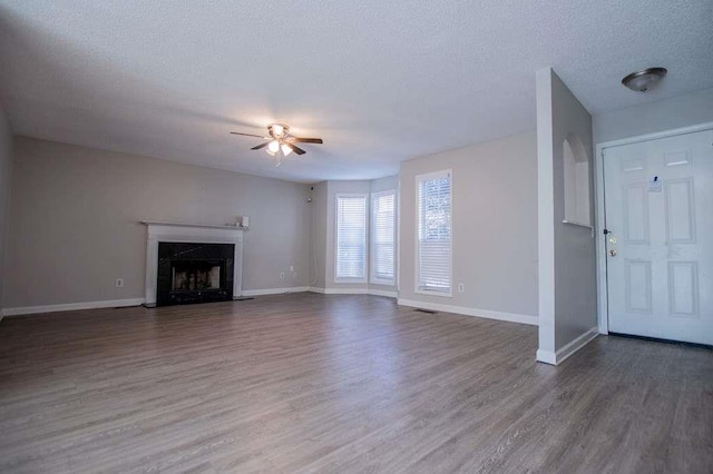 unfurnished living room with ceiling fan, hardwood / wood-style floors, a fireplace, and a textured ceiling