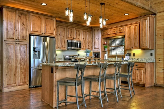 kitchen featuring a center island, hanging light fixtures, light stone counters, dark hardwood / wood-style floors, and appliances with stainless steel finishes