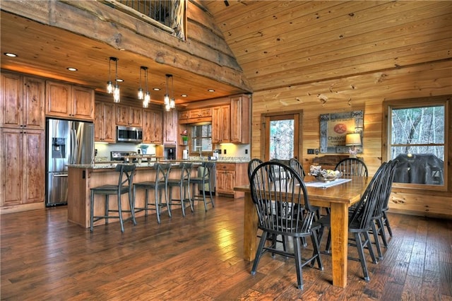 dining room with wooden walls, dark hardwood / wood-style flooring, wood ceiling, and high vaulted ceiling