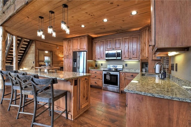 kitchen featuring sink, light stone counters, pendant lighting, a breakfast bar area, and appliances with stainless steel finishes