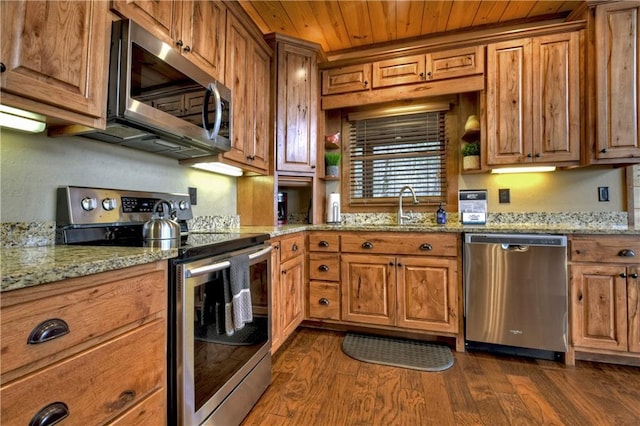 kitchen with appliances with stainless steel finishes, light stone counters, dark wood-type flooring, and sink