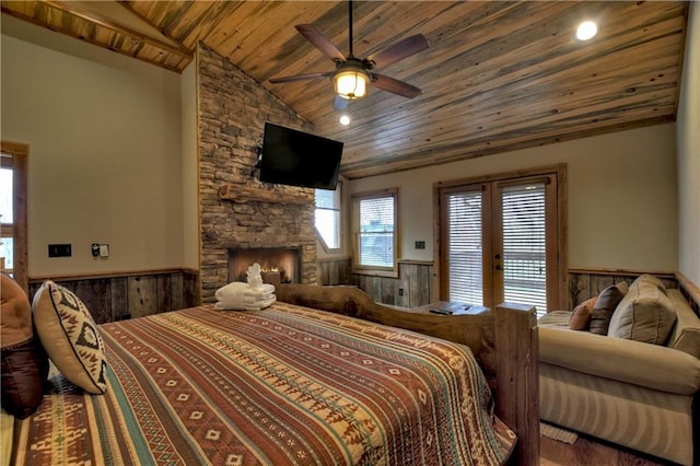 bedroom featuring ceiling fan, wooden ceiling, a stone fireplace, wood walls, and vaulted ceiling