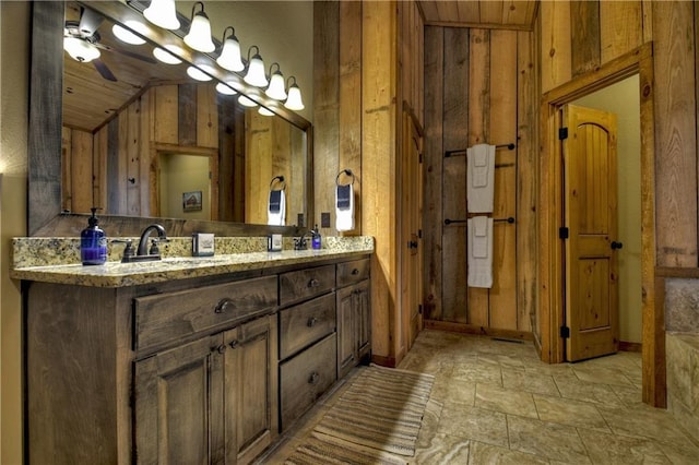 bathroom with vanity, wooden walls, and ceiling fan