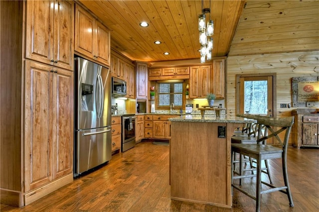 kitchen with light stone counters, a breakfast bar, stainless steel appliances, dark hardwood / wood-style floors, and hanging light fixtures