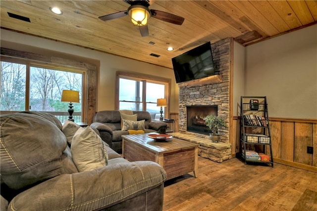 living room featuring a fireplace, light hardwood / wood-style flooring, wood walls, and wood ceiling